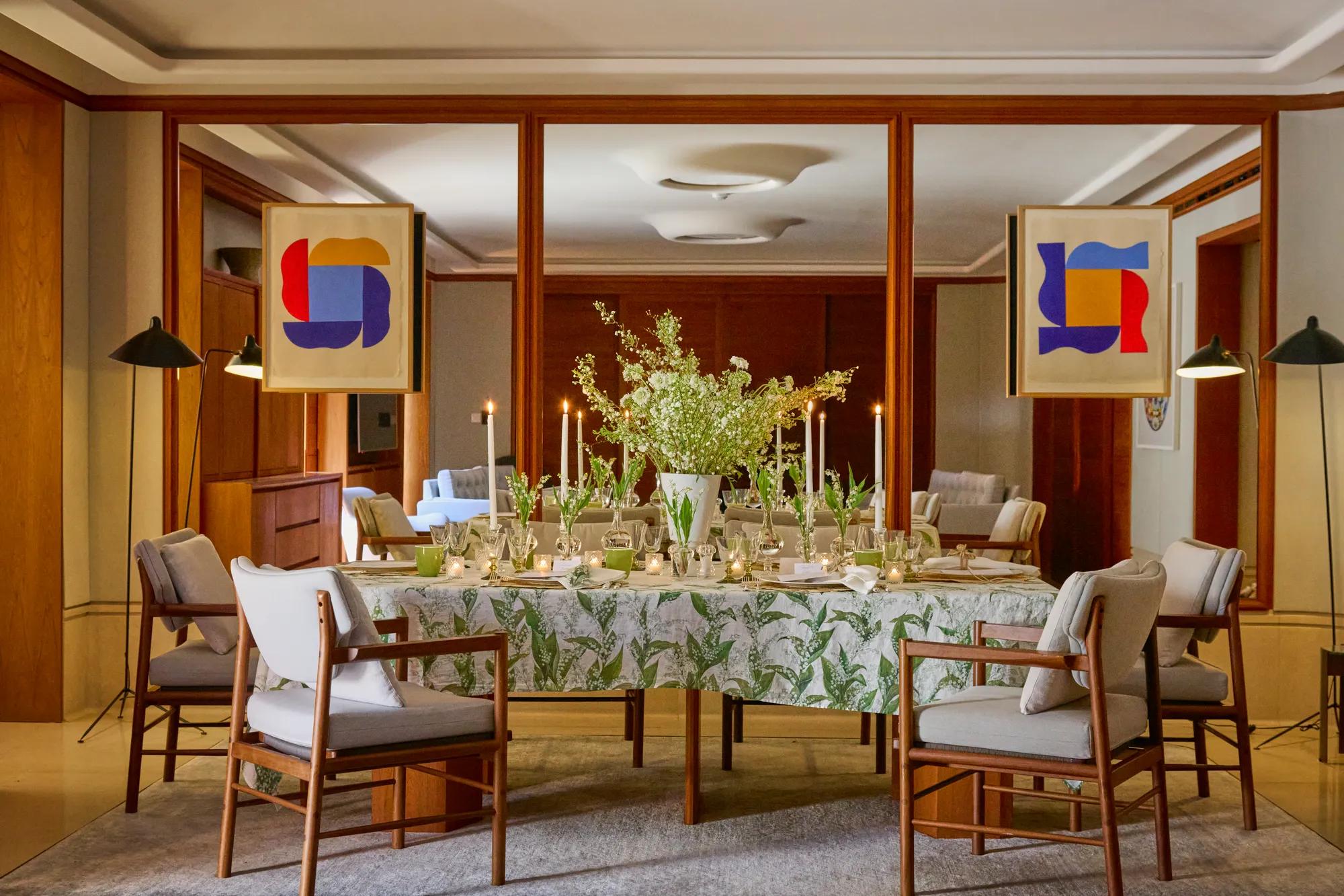 Elegant dining room with a floral table setting, surrounded by upholstered chairs and framed abstract artwork.