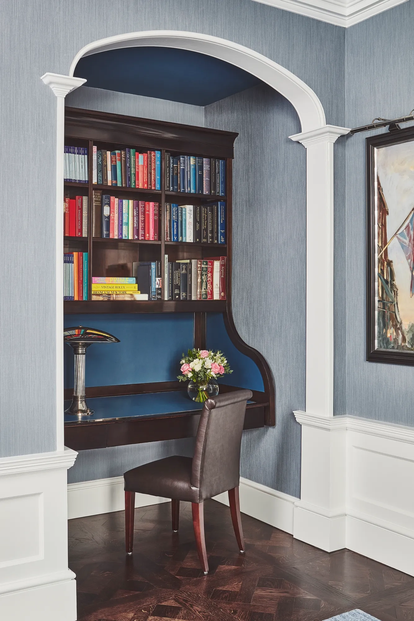 Built-in writing nook with dark wood desk, bookshelves filled with colorful books, and a single chair.