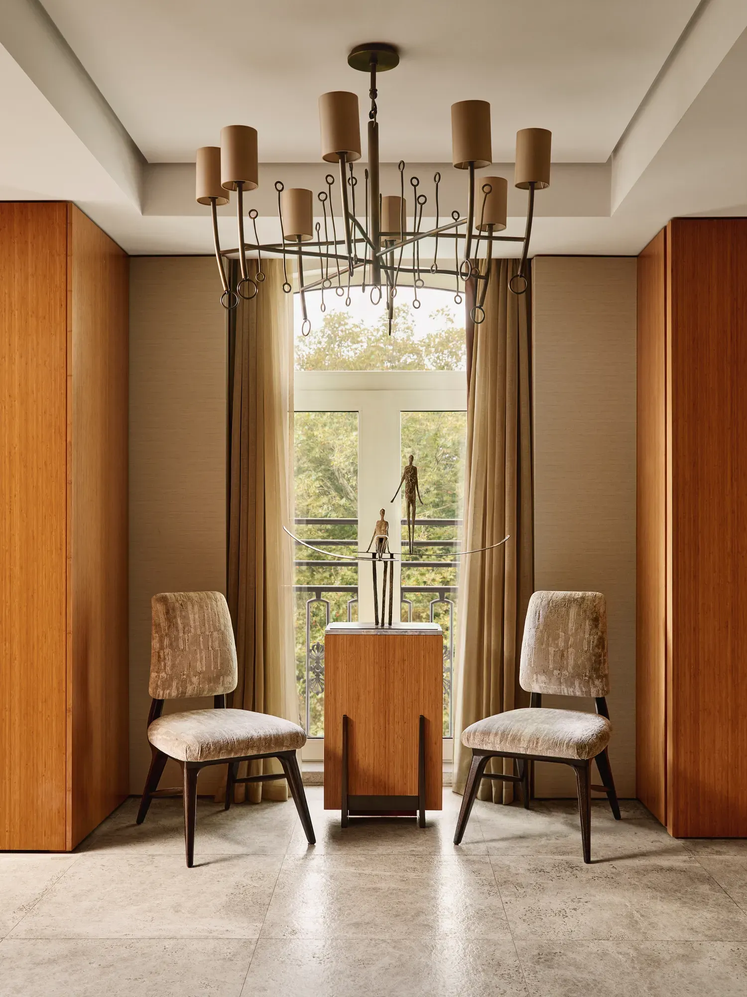 Seating alcove with two chairs, side table, and decorative sculpture beneath a chandelier in the Opus Suite