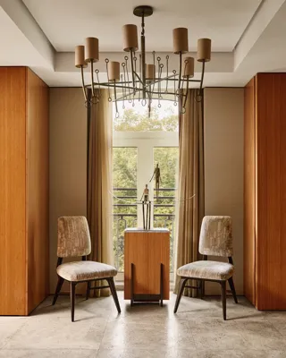 Seating alcove with two chairs, side table, and decorative sculpture beneath a chandelier in the Opus Suite