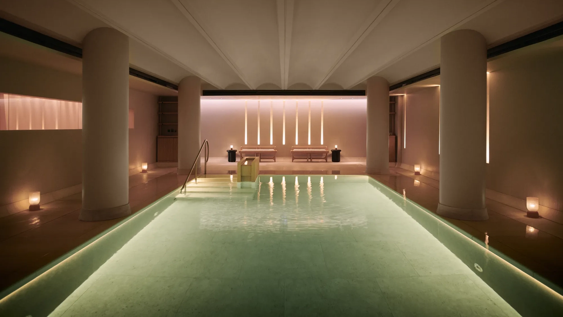 Serene indoor pool at Claridge’s spa, softly lit with candles and warm ambient lighting.