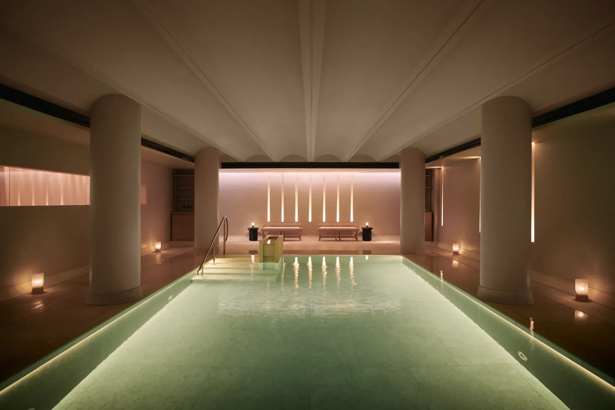 Serene indoor pool at Claridge’s spa, softly lit with candles and warm ambient lighting.