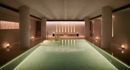 Serene indoor pool at Claridge’s spa, softly lit with candles and warm ambient lighting.