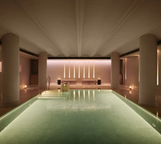 Serene indoor pool at Claridge’s spa, softly lit with candles and warm ambient lighting.