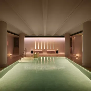 Serene indoor pool at Claridge’s spa, softly lit with candles and warm ambient lighting.