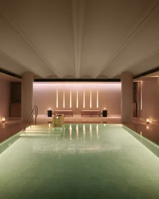 Serene indoor pool at Claridge’s spa, softly lit with candles and warm ambient lighting.