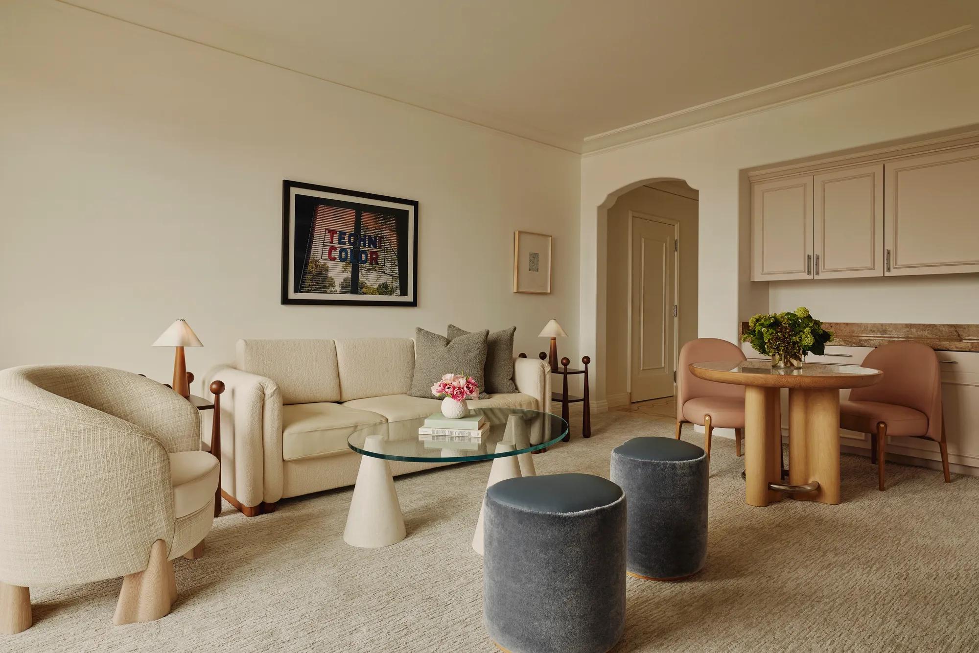 Two-Bedroom Library Suite living area with sofa, armchairs, round dining table, and elegant neutral-toned décor.