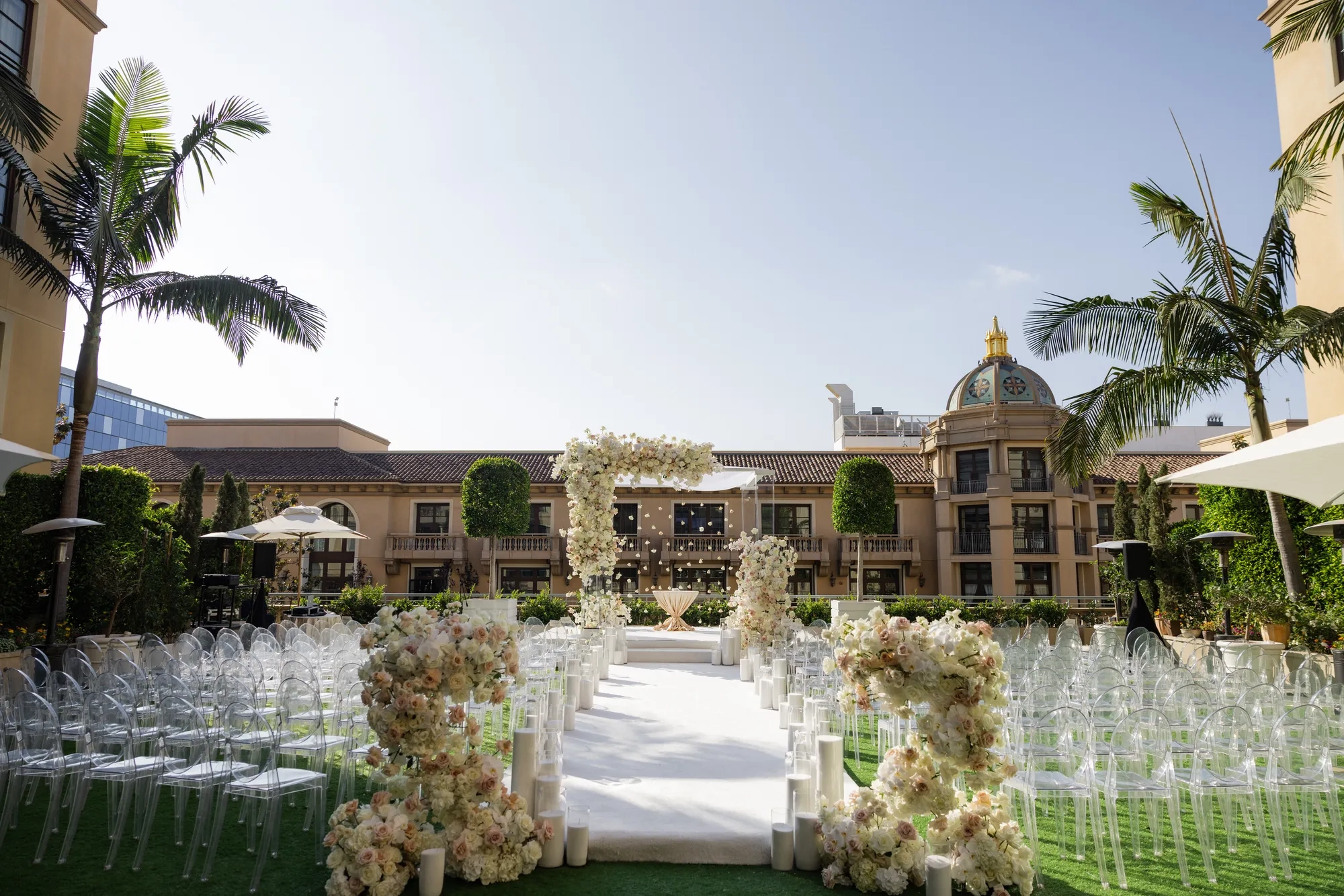 Beverly Hills garden terrace dinner setup with rattan chairs, green centerpieces, and string lights overhead.