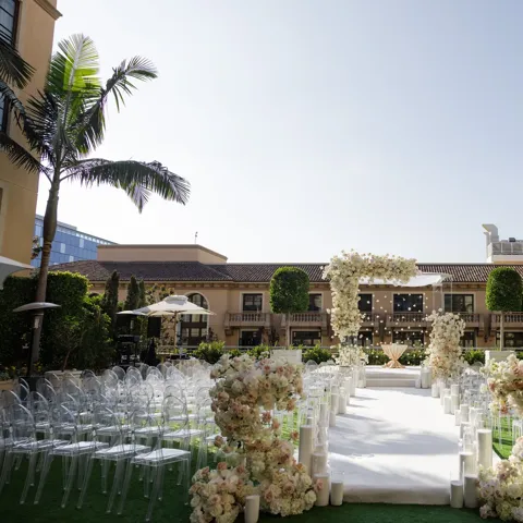 Beverly Hills garden terrace dinner setup with rattan chairs, green centerpieces, and string lights overhead.