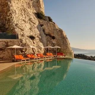A serene swimming pool at Maybourne Riviera, featuring sleek contemporary design and expansive views over the Mediterranean coastline.