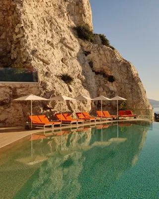 A serene swimming pool at Maybourne Riviera, featuring sleek contemporary design and expansive views over the Mediterranean coastline.